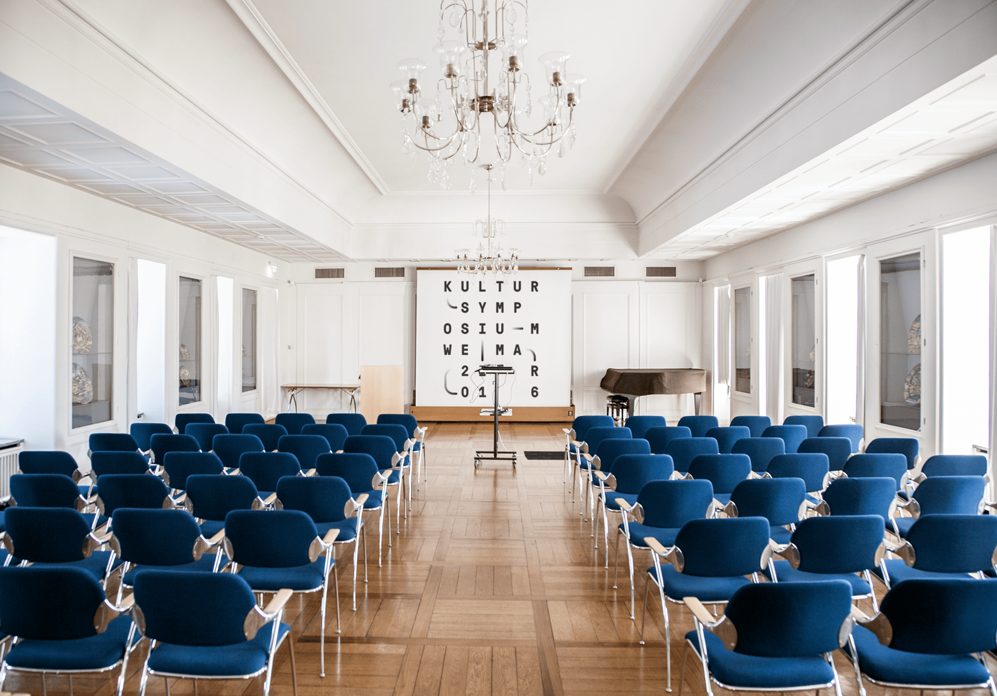 Leerer Konferenzraum mit blauen Stühlen und grafischem Keyvisual / Empty conference room with blue chairs and graphic key visual