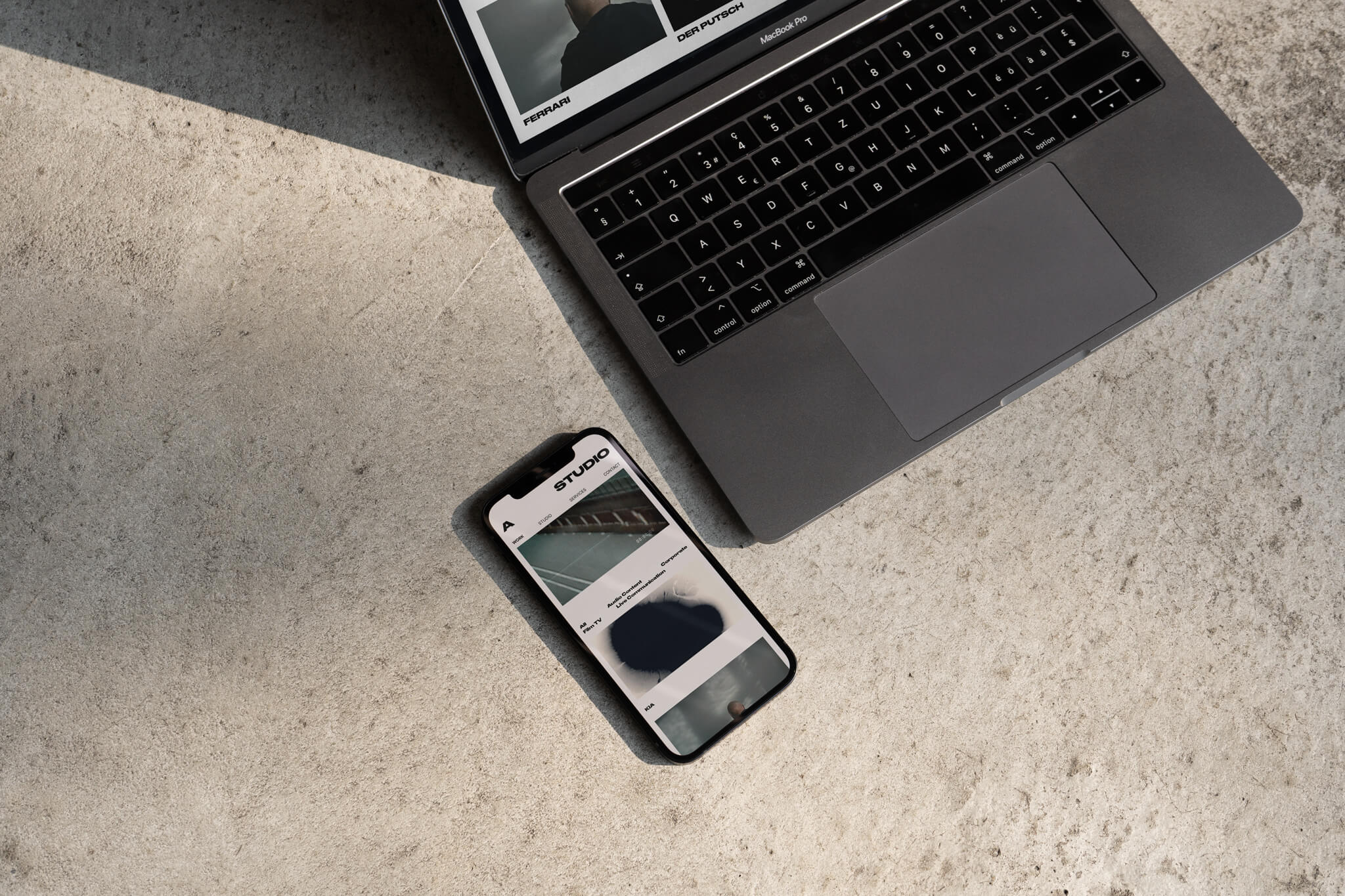 Smartphone und Laptop im Anschnitt auf steinigem Boden / Smartphone und Laptop auf steinigem Boden